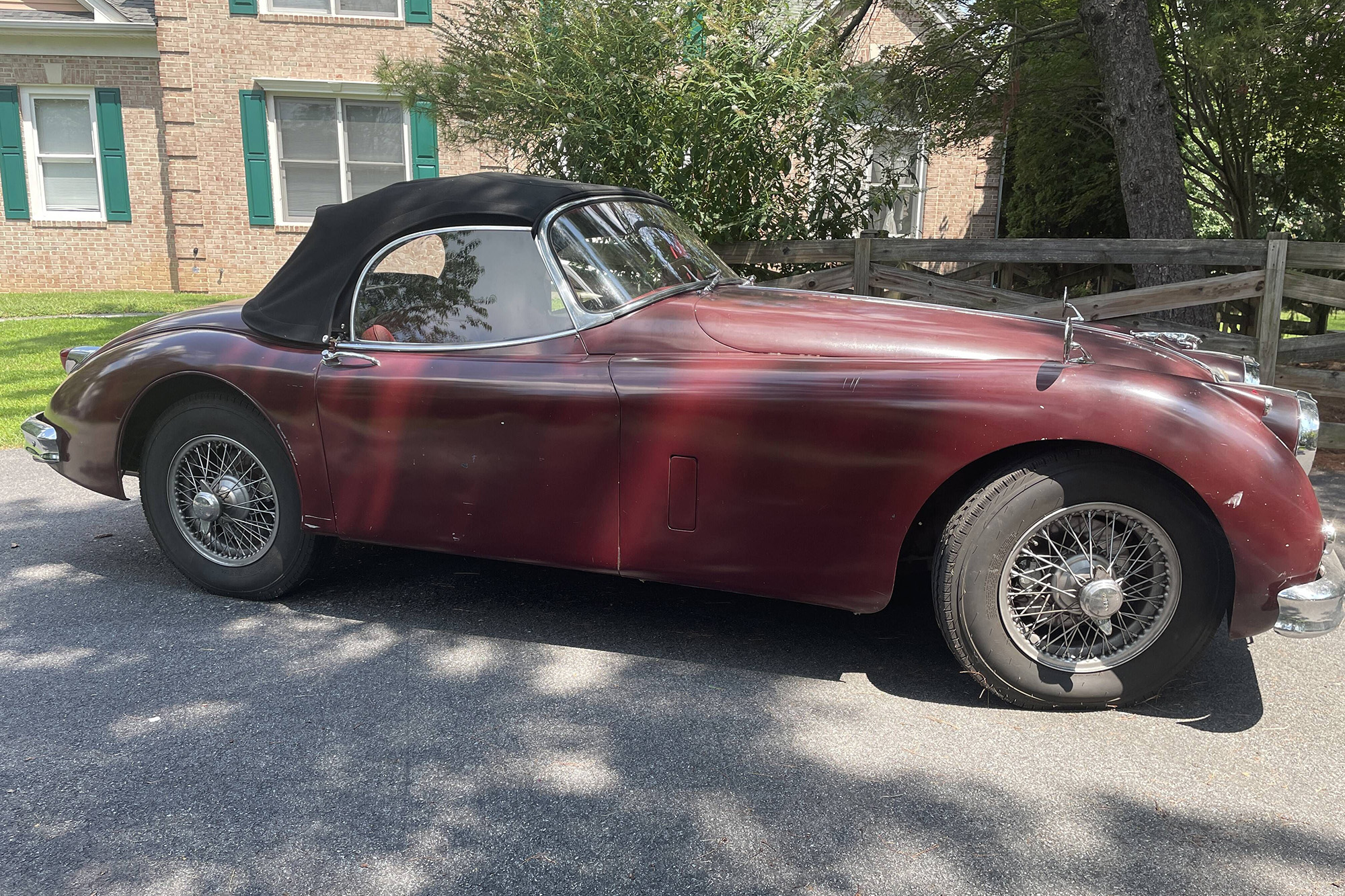 1959 Jaguar XK150 Roadster, side view, maroon with a black top, top up