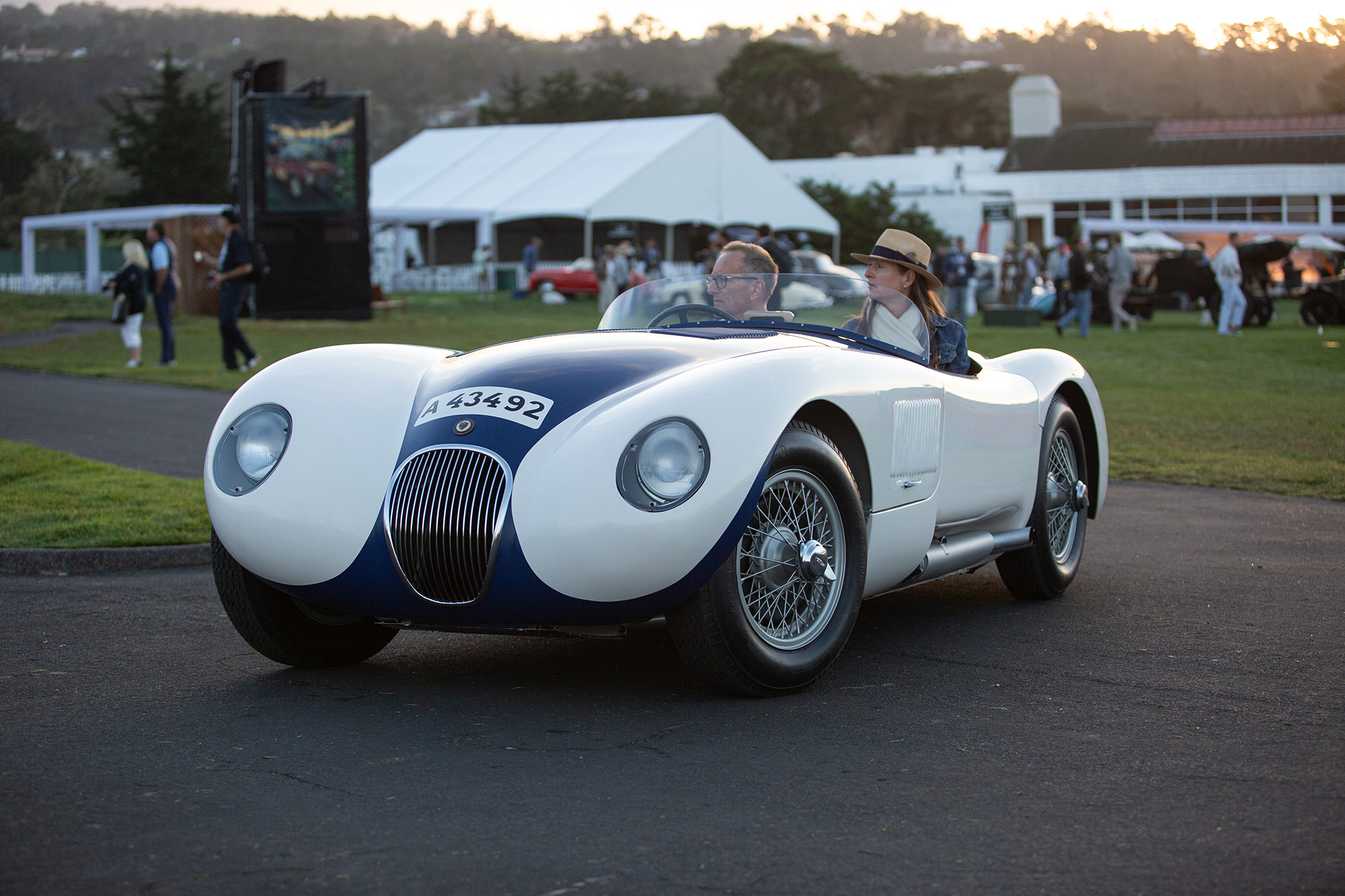 1953 Jaguar C-type, front quarter, white with blue stripe, entering the Pebble Beach show field.