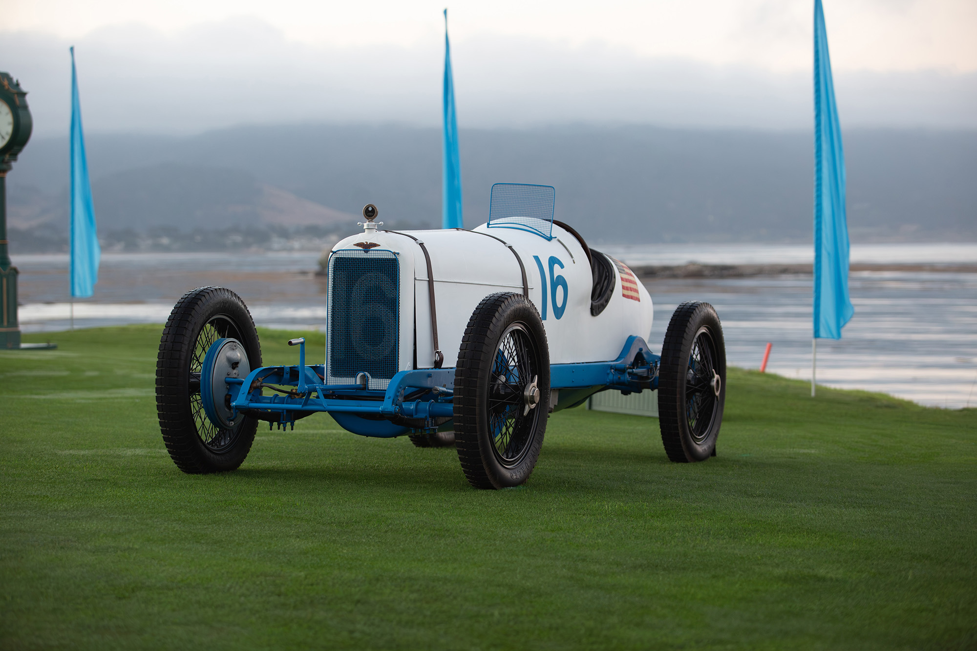 1921 Duesenberg 183 Grand Prix, front quarter, number 16, on the grass at Pebble Beach with the bay behind it