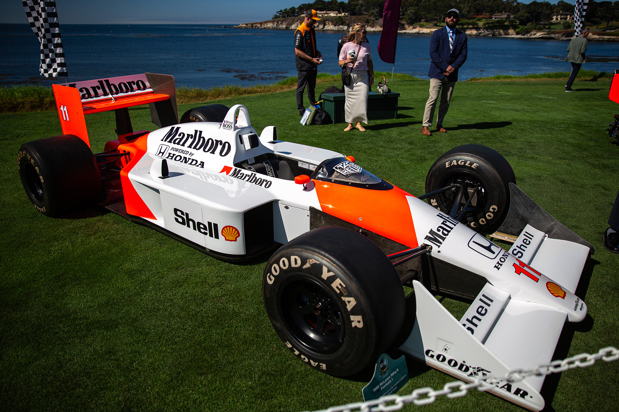 1988 McLaren MP4/4, front quarter, Marlboro livery, on the grass at Pebble Beach Concours with the ocean behind it